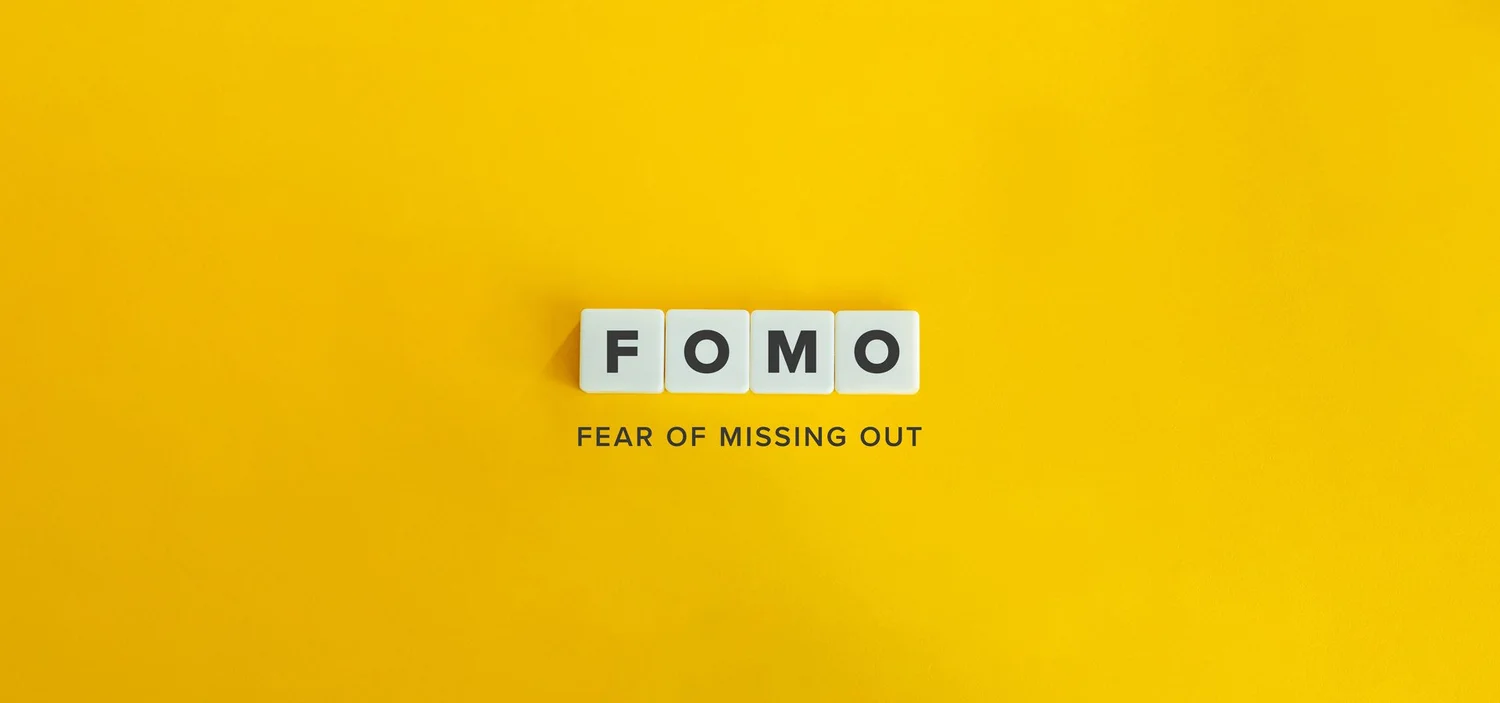 Graphic representation of the acronym 'FOMO,' standing for 'Fear of Missing Out,' with each letter displayed on a separate die