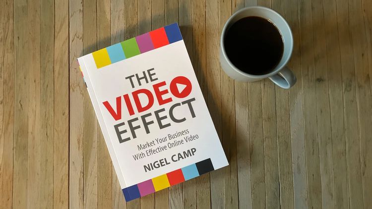 A copy of The Video Effect by Nigel Camp on a wooden table beside a cup of coffee.