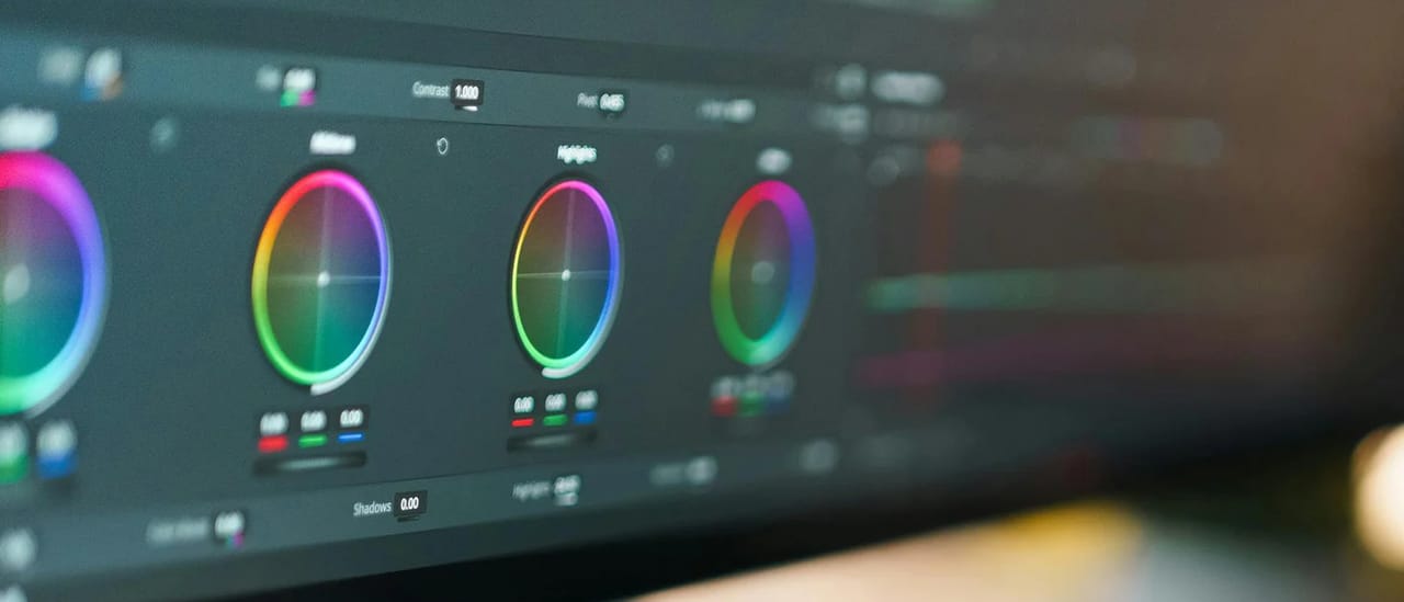 A colour-grading panel on an editing monitor, with three colour wheels glowing in soft focus.