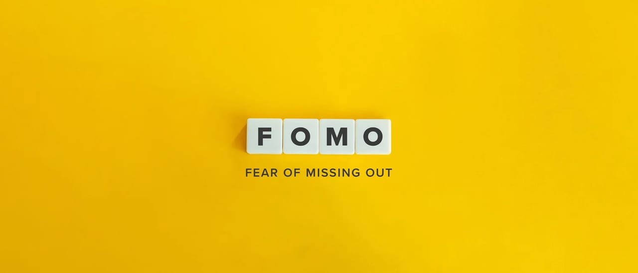 Letter tiles spelling FOMO above the words "fear of missing out" on a bright yellow background.