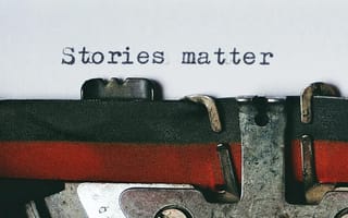 Close-up of a vintage typewriter with a sheet of paper reading "Stories matter".