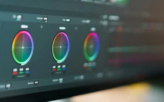A colour-grading panel on an editing monitor, with three colour wheels glowing in soft focus.