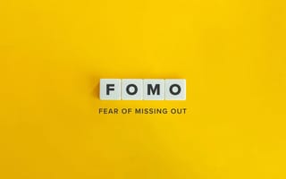 Letter tiles spelling FOMO above the words "fear of missing out" on a bright yellow background.