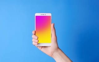 A hand holding a smartphone upright, its screen glowing pink, against a plain blue background.