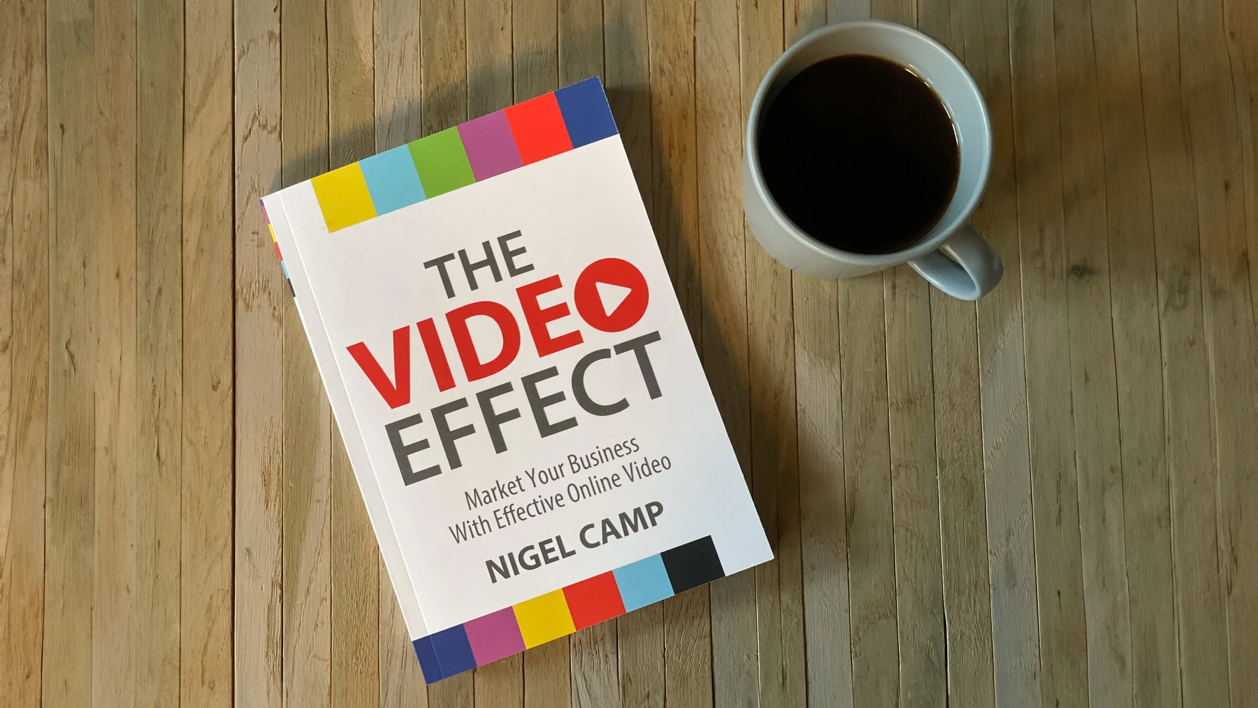 A copy of The Video Effect by Nigel Camp on a wooden table beside a cup of coffee.
